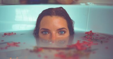 woman in bathtub with red flower petals floating on water