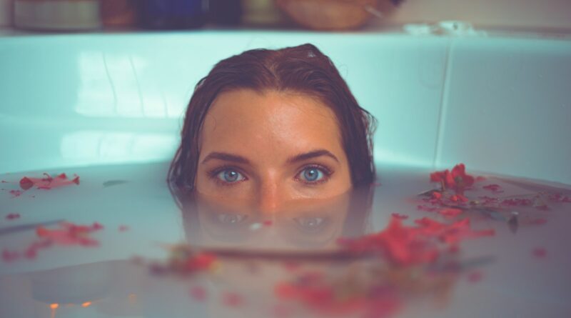 woman in bathtub with red flower petals floating on water