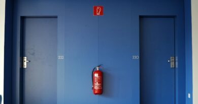 Blue doors in a corridor with a red fire extinguisher between them.