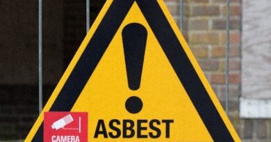 A yellow and black warning sign on a fence
