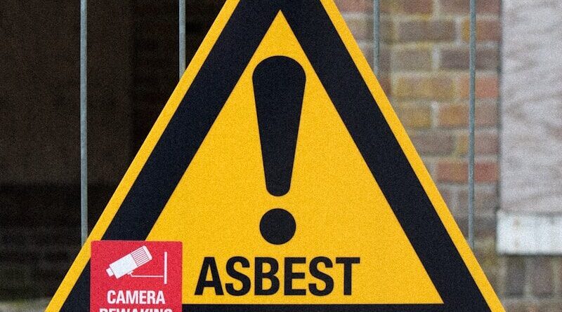 A yellow and black warning sign on a fence